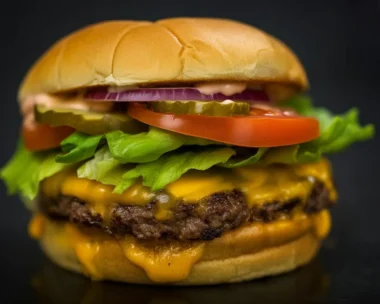 Delicious All-American Cheeseburger with cheese, pickles, and condiments on a sesame bun.
