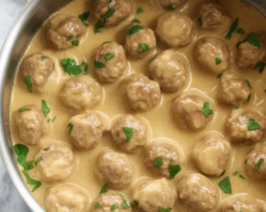 Homemade Swedish meatballs in creamy gravy served with noodles and parsley garnish.