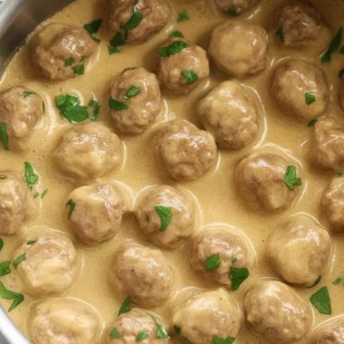 Homemade Swedish meatballs in creamy gravy served with noodles and parsley garnish.