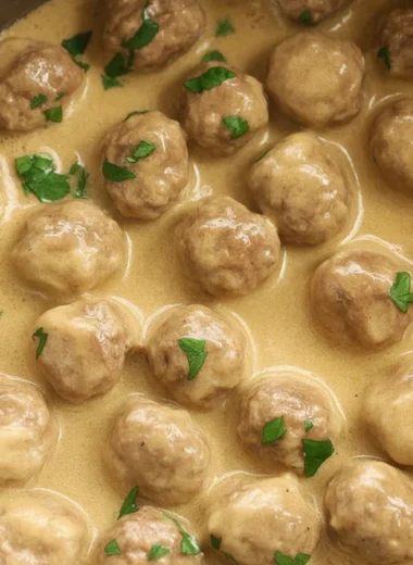 Homemade Swedish meatballs in creamy gravy served with noodles and parsley garnish.