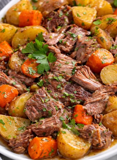 Delicious Slow Cooker Pot Roast with Potatoes, Carrots, and rich beef broth served on platter.