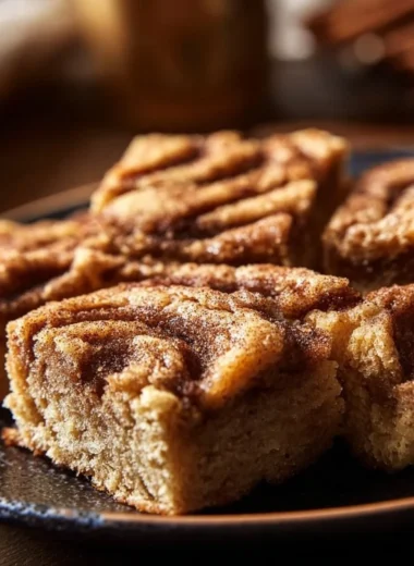 Cinnamon Swirl Snickerdoodle Blondies stacked on a plate with a sprinkle of cinnamon