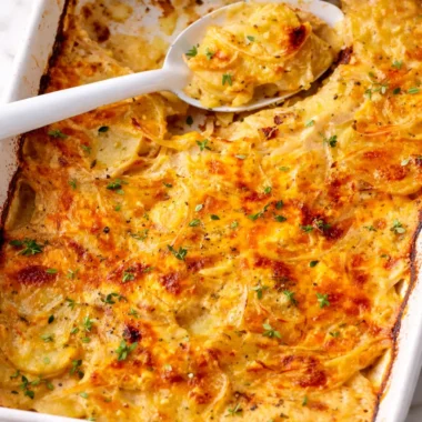 Delicious scalloped potatoes layered in creamy cheese sauce, perfect holiday side dish.