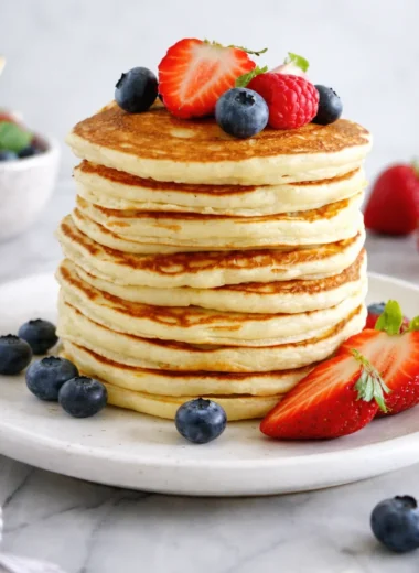 Delicious fluffy American pancakes topped with fresh berries and syrup.