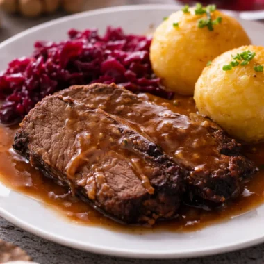 Traditional Sauerbraten served with sweet and sour gravy on a plate.