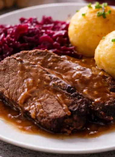 Traditional Sauerbraten served with sweet and sour gravy on a plate.