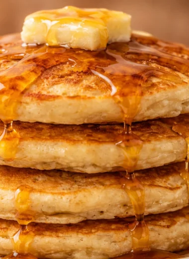Delicious thick and fluffy pancakes stacked on a plate with syrup