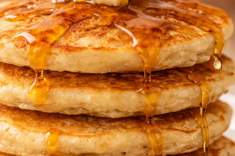 Delicious thick and fluffy pancakes stacked on a plate with syrup