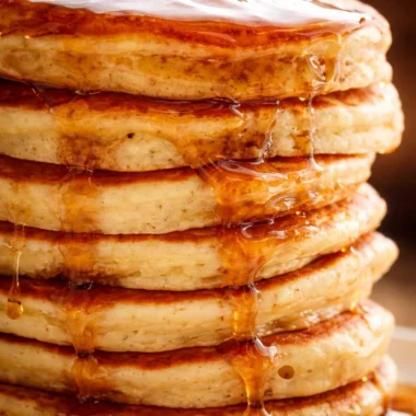 Delicious homemade fluffy pancakes served with syrup and fresh berries.