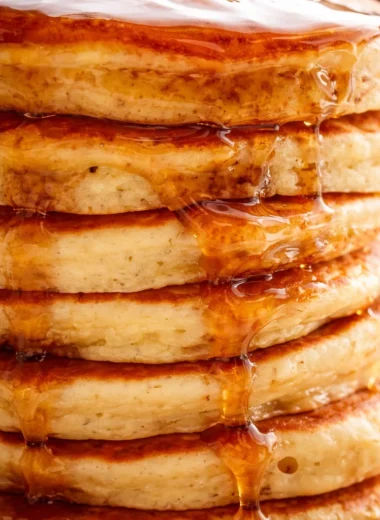 Delicious homemade fluffy pancakes served with syrup and fresh berries.