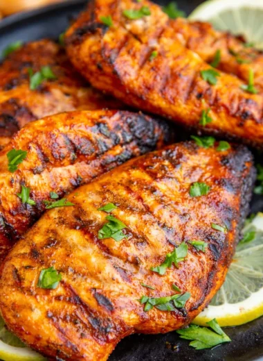 Juicy grilled chicken breast on the grill with seasoning, ready for serving.