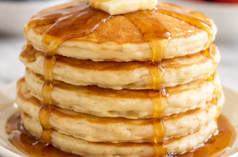 The world's best pancakes stacked high, fluffy and golden, served with syrup.