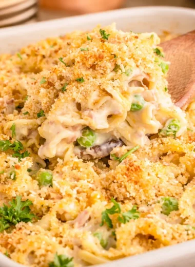 Delicious Tuna Noodle Casserole with pasta, tuna, peas, and cheesy topping.
