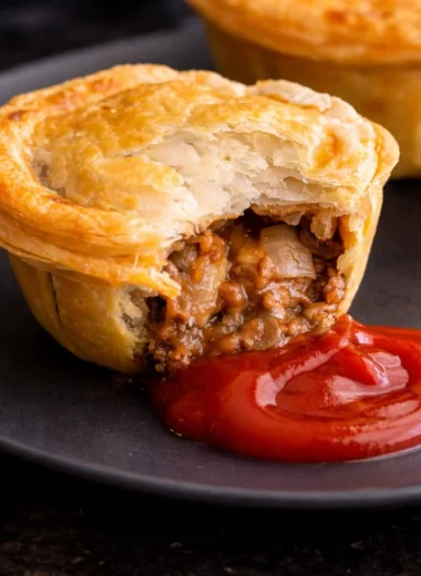 Delicious Australian party pies with flaky pastry and savory beef filling on a plate.