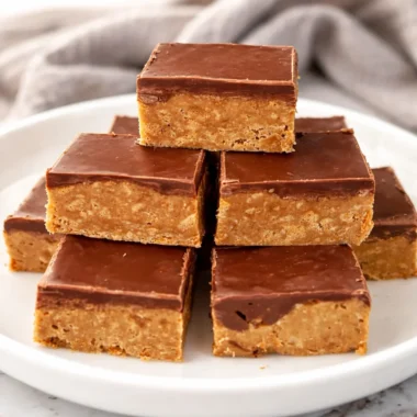 Delicious homemade Tim Tam slice served on a plate with chocolate drizzle.