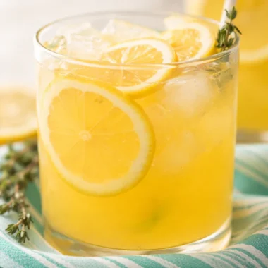 Refreshing glass of Sweet Tart Peach Lemonade with peaches and lemon slices.