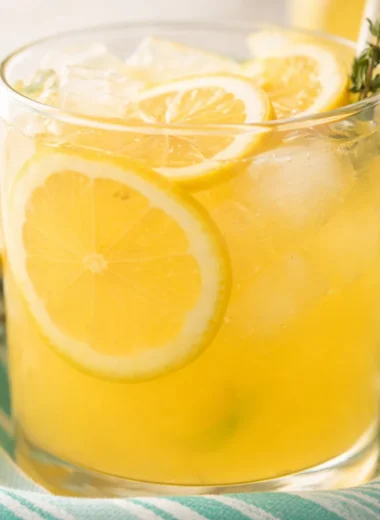 Refreshing glass of Sweet Tart Peach Lemonade with peaches and lemon slices.