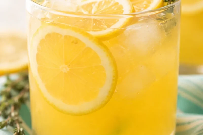 Refreshing glass of Sweet Tart Peach Lemonade with peaches and lemon slices.