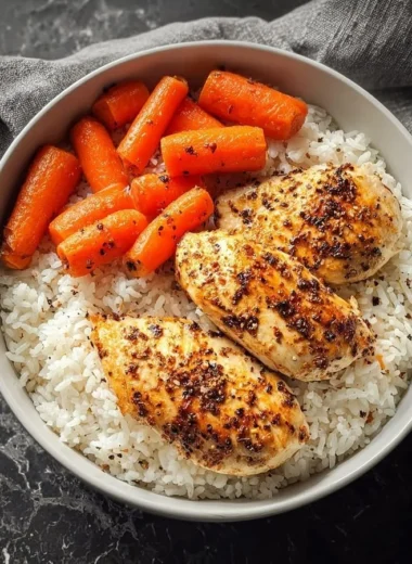 Black pepper chicken breast served with rice and glazed carrots on a plate