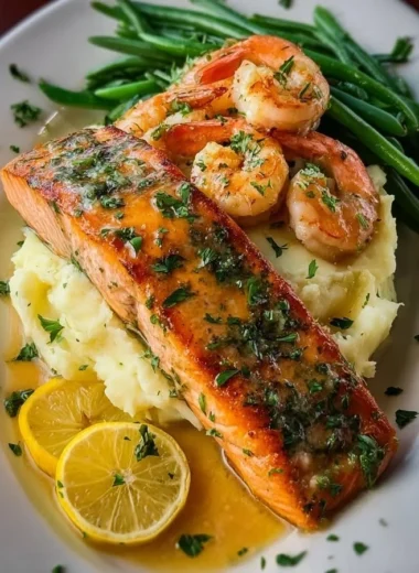Creamy mashed potatoes served with garlic butter salmon and shrimp on a plate.