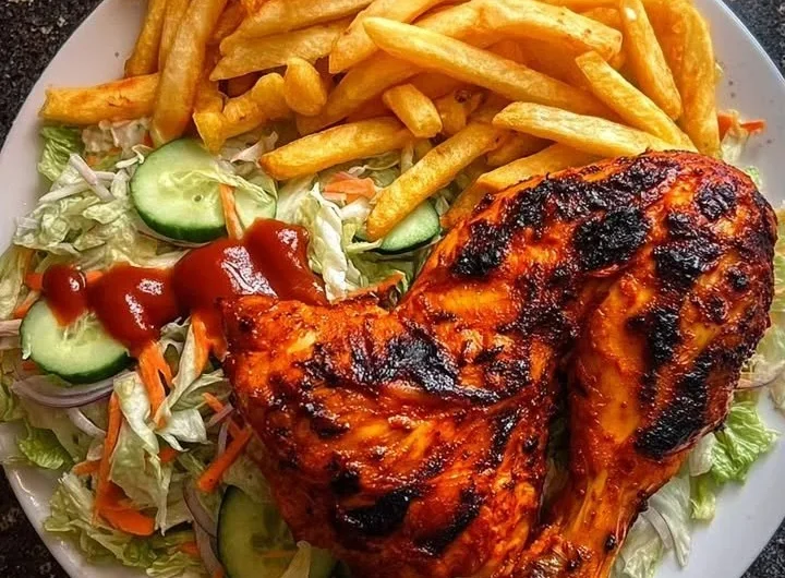 Flame-grilled chicken leg quarters with fries and salad on a plate