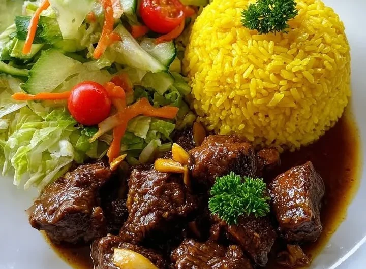 Delicious Garlic Beef Bites served with yellow rice and a colorful garden salad