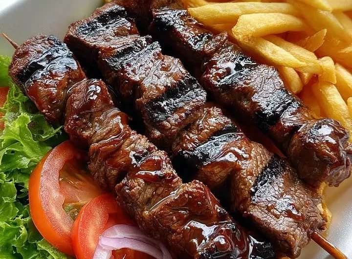Delicious grilled beef skewers served with crispy fries on a plate