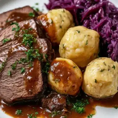 Traditional Sauerbraten dish served with gravy and side vegetables
