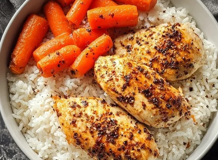 Black pepper chicken breast served with rice and glazed carrots on a plate