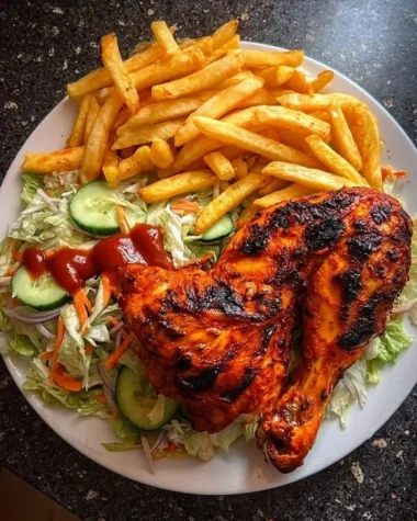 Flame-grilled chicken leg quarters with fries and salad on a plate